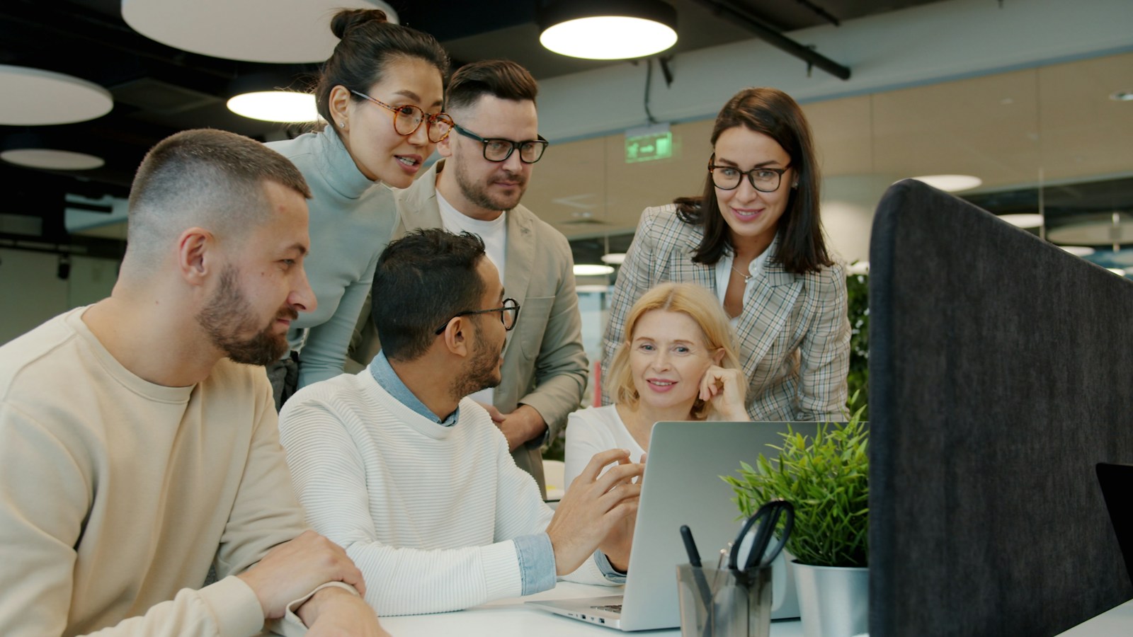Sales colleagues collaborating around a laptop in a modern office